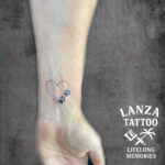 Fine line heart tattoo with dotted details, created at Lanza Tattoo in Puerto del Carmen.